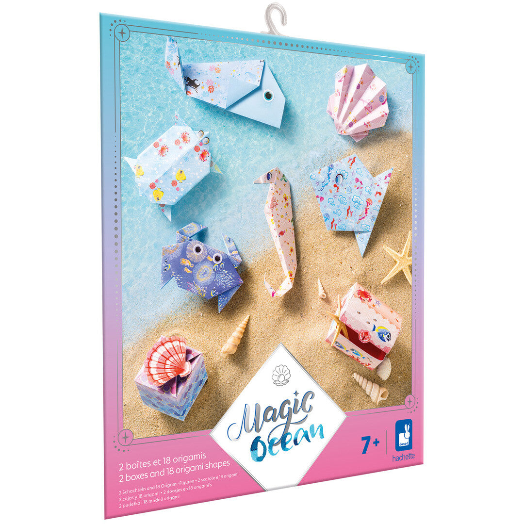 Verpakking van de Janod Magic Ocean origami knutselset met diverse gevouwen zeedieren en doosjes op een strandachtergrond.