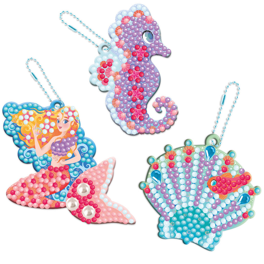 Drie afgewerkte Magic Ocean Diamond Painting sleutelhangers: een zeemeermin, een zeepaardje en een schelp.