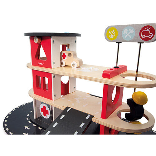 Detail van de Janod houten brandweerkazerne speelset met een ambulance op de bovenste verdieping.