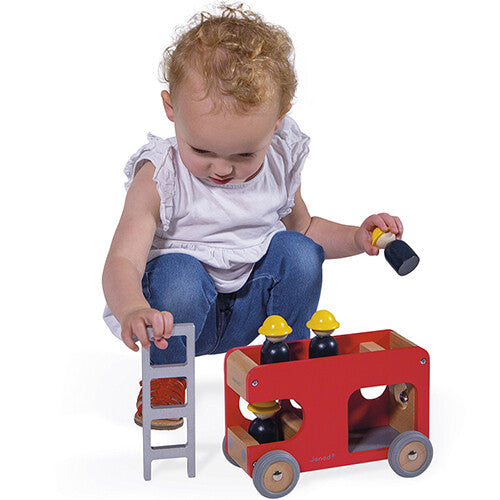 Een meisje speelt met de Janod houten brandweerwagen en houdt de ladder vast.