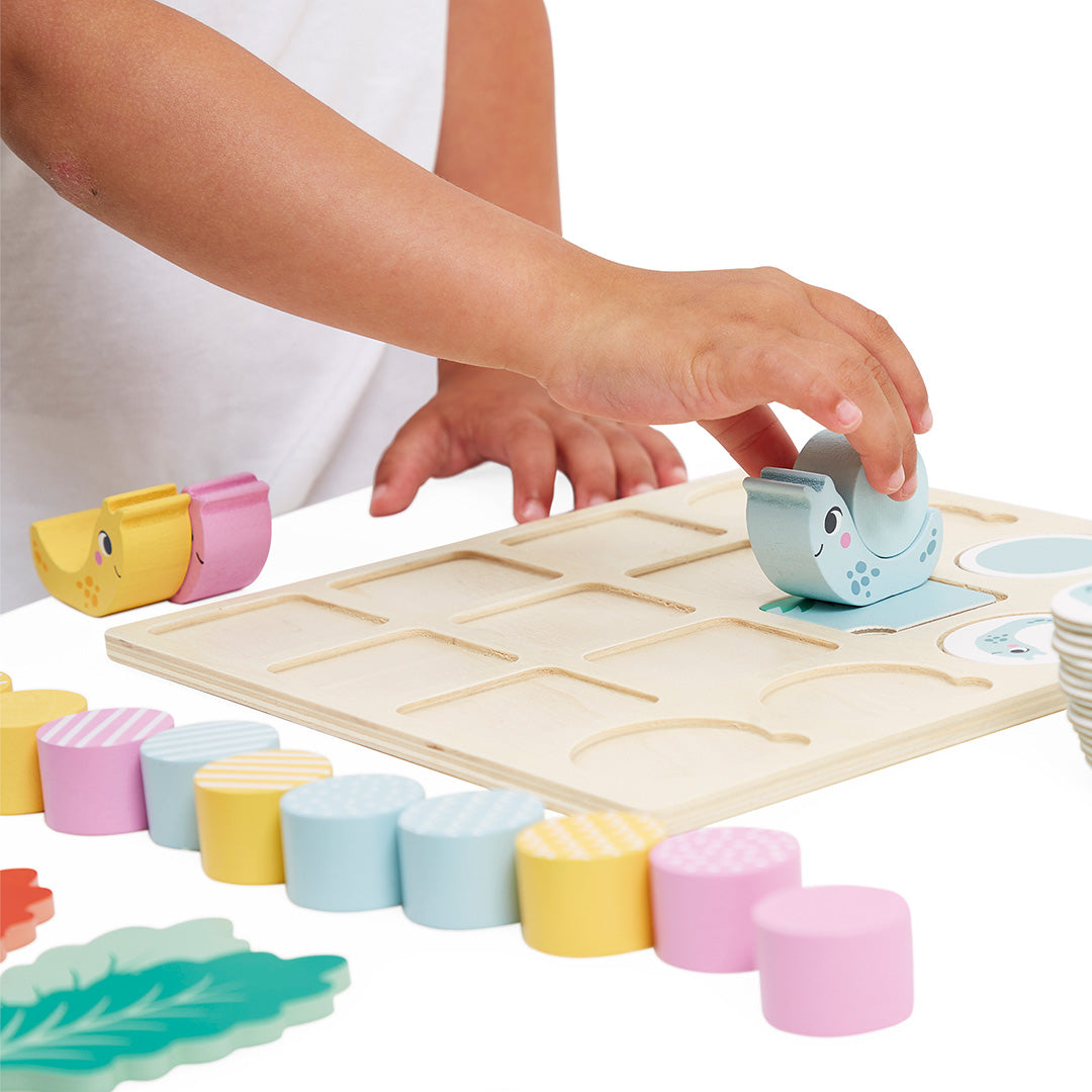 Kinderhanden plaatsen een blauwe slak op het houten speelbord van het Janod educatieve spel.