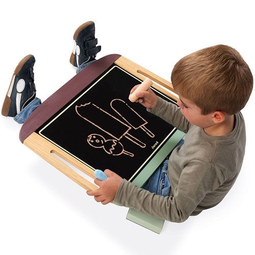 Een kind tekent met krijt op het Janod draagbare krijtbord, van bovenaf gezien.