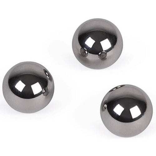 Drie glimmende metalen balletjes voor de flipperkast liggen op een witte ondergrond.