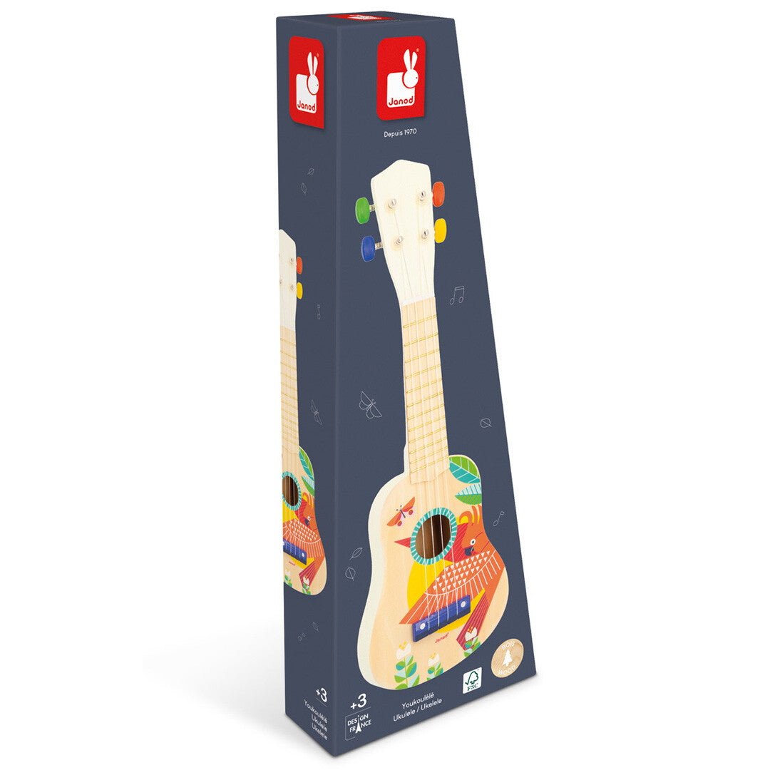 De Janod verpakking van de houten kinderukelele met vogelprint, schuin gefotografeerd.