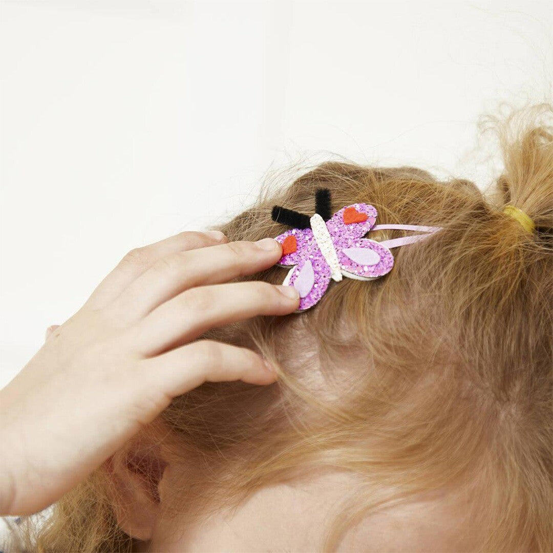 Een kind draagt een paars glitter vlinder haarclipje in blond haar.