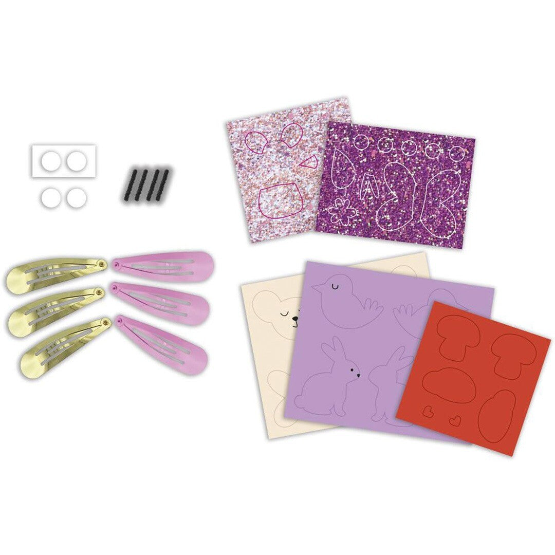 De onderdelen van de Janod knutselset voor haarclipjes, inclusief clipjes, vilt en glittermateriaal.