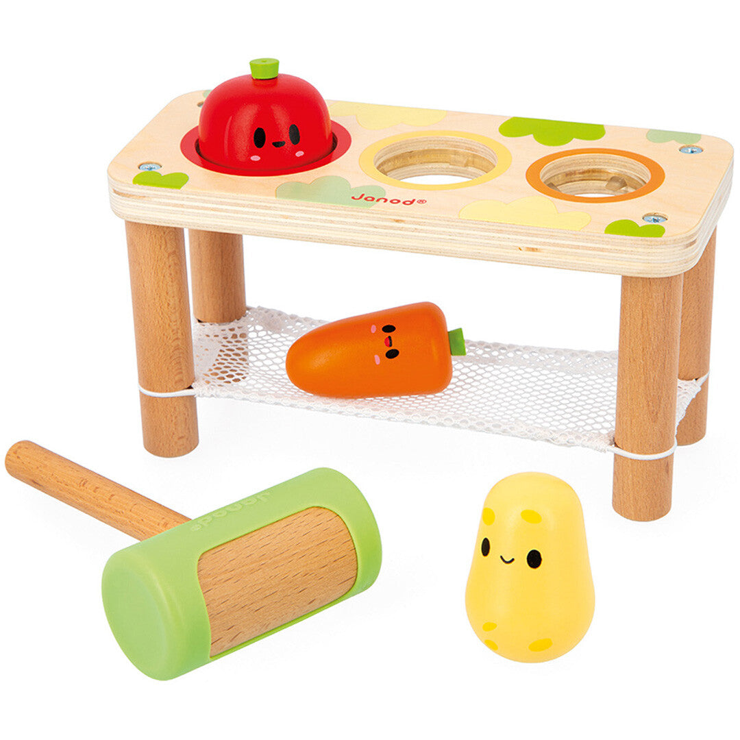 Janod hamerbank babyspeelgoed met een rood appelvormig figuur erin, een oranje wortel en gele aardappel ernaast, en een hamer.