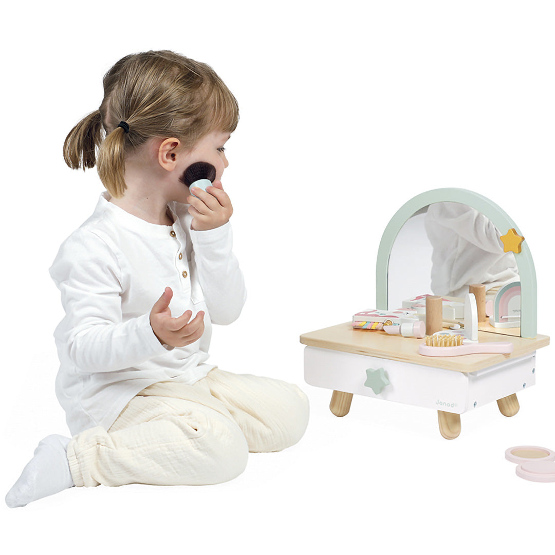 Een kind speelt met het Janod houten eenhoorn kaptafeltje en brengt make-up aan.