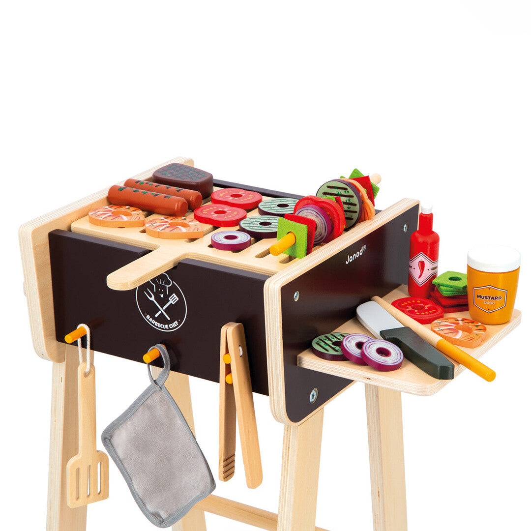Detailopname van de Janod kinderbarbecue met houten speelgoedeten zoals worstjes, garnalen en groentespiesjes.