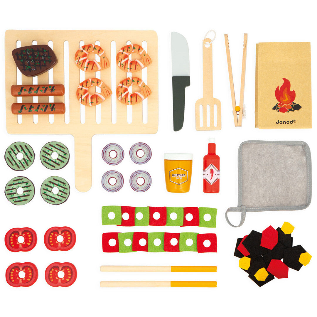 Alle losse onderdelen van de Janod houten kinderbarbecue set, inclusief speelgoedeten en accessoires, van bovenaf gezien.