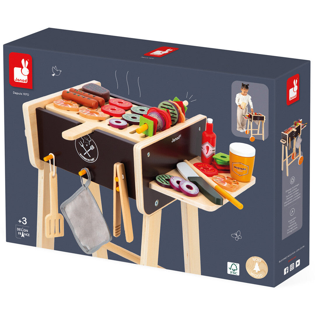 De verpakking van de Janod houten kinderbarbecue set met een afbeelding van het speelgoed.