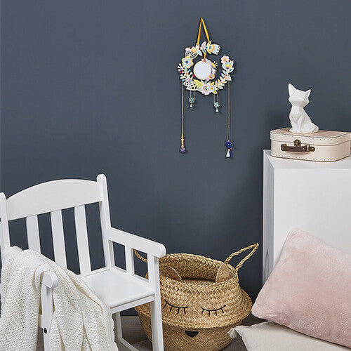 De Janod bloemige sieradenhouder met spiegel hangt aan de muur in een kinderkamer.