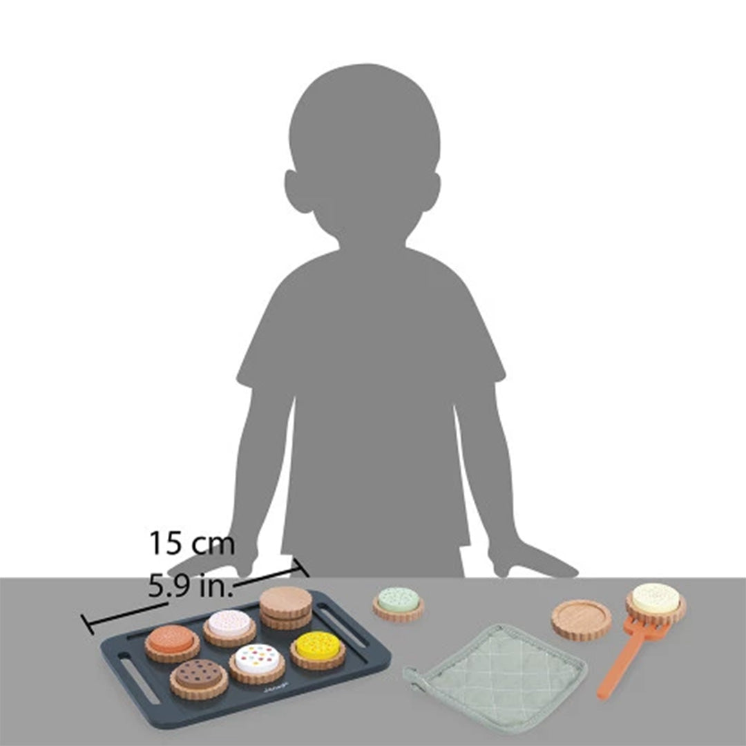 De Janod houten koekjes bakken speelset naast een kindersilhouet om de schaal van het speelgoed te tonen.