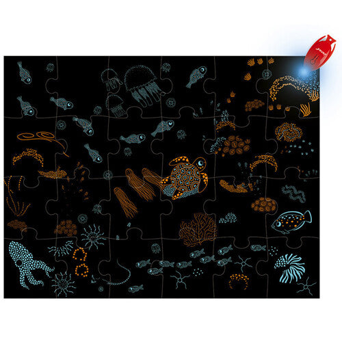 De Janod magische legpuzzel 'De Oceaan' toont een donkere onderwaterwereld met oplichtende dieren en koralen.