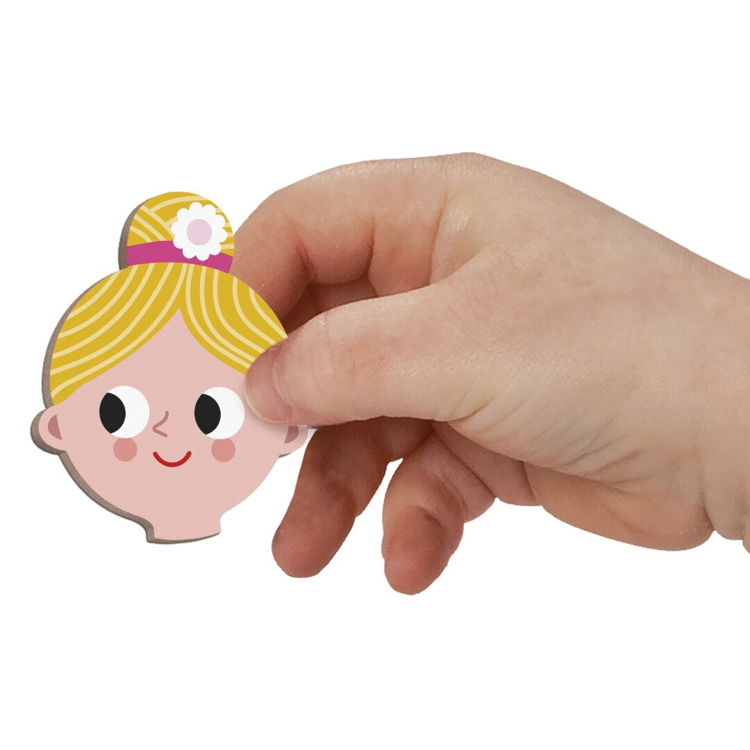 Een kinderhand houdt een Janod magnetisch hoofdje met blond haar en een roze haarband vast.