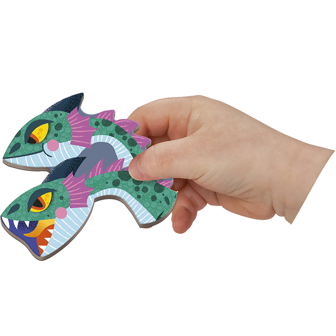 Een kinderhand houdt twee stukken van een blauwgroene drakenmagneet vast.