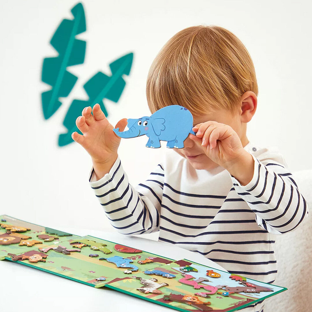 Een kind speelt met een blauwe olifant magneet van het Janod Magnéti'stories magnetisch speelboek met Afrikaanse dieren.