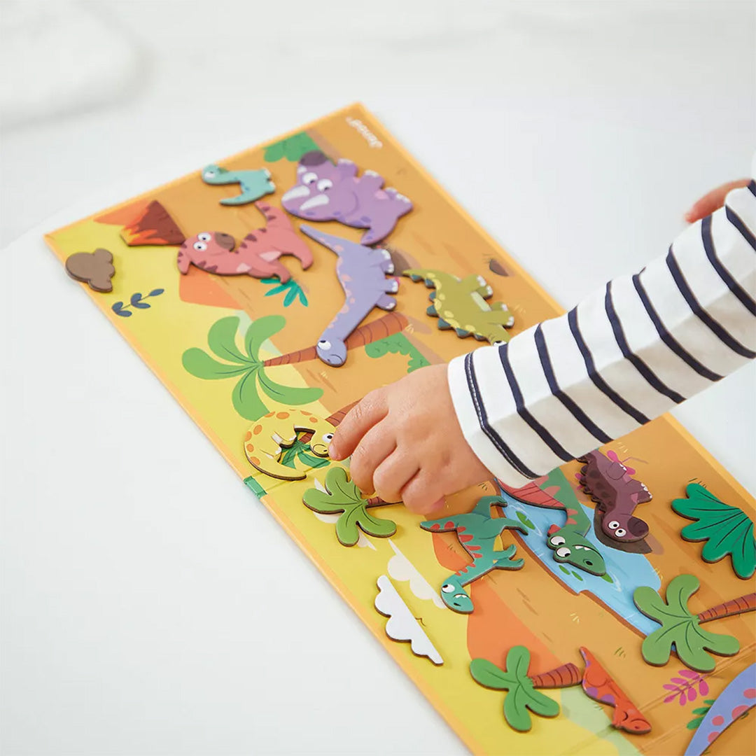 Een kind speelt met de Janod Magnéti'stories dinosaurus magneten op de opengeklapte speelplaat.