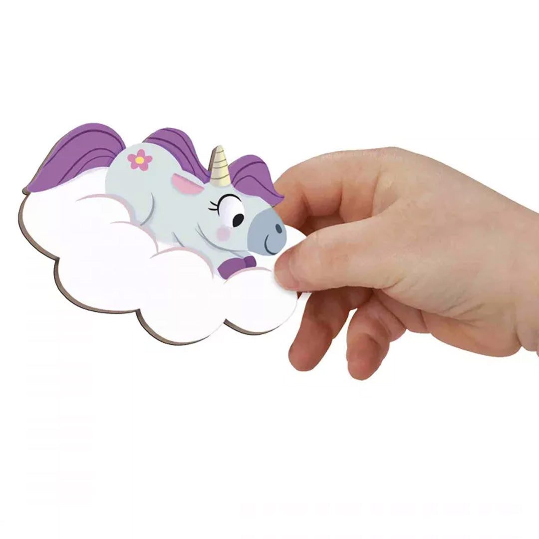 Een kinderhand houdt een Janod eenhoorn magneetstuk op een wolk magneet vast om de grootte te tonen.
