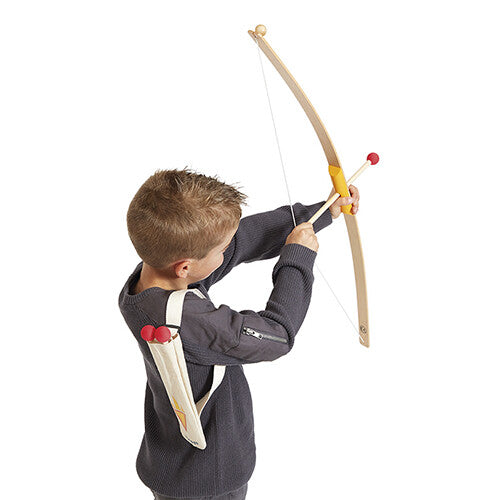 Een jongen richt met de Janod houten pijlen en boog, met een pijlenkoker op zijn rug.