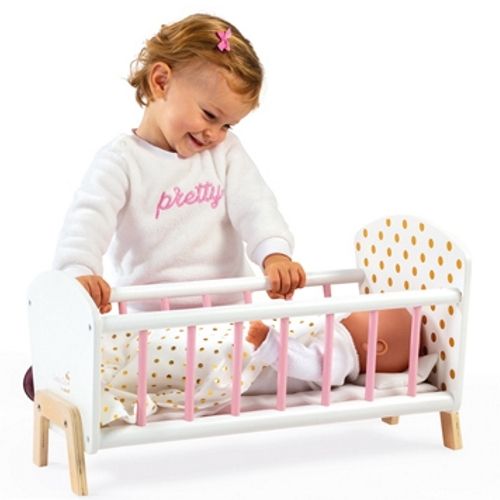 Een kind speelt met het Janod houten poppenbed waarin een pop ligt.