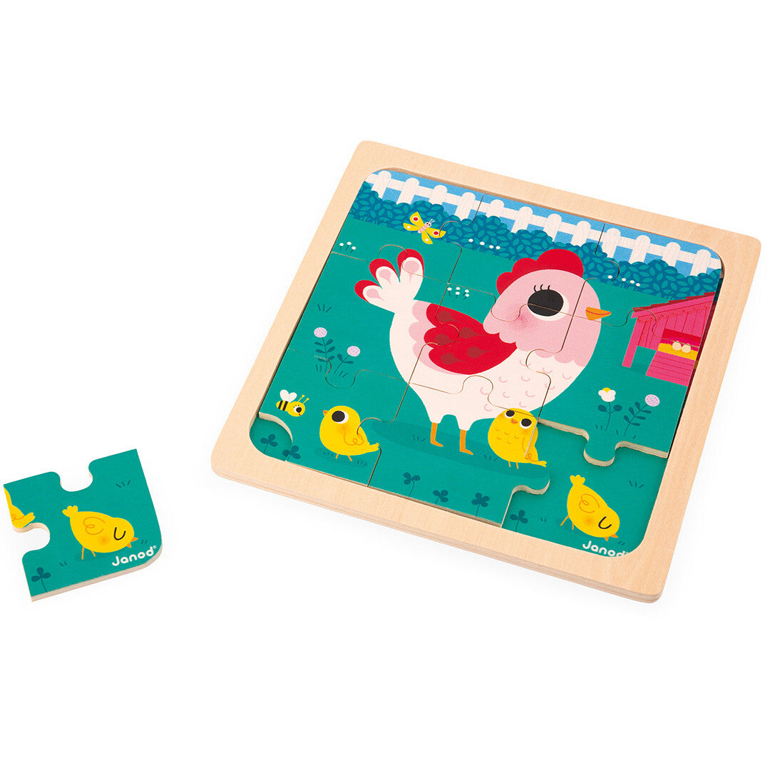 Janod houten puzzel met een kip en kuikens op een boerderij, met één los puzzelstuk ernaast.