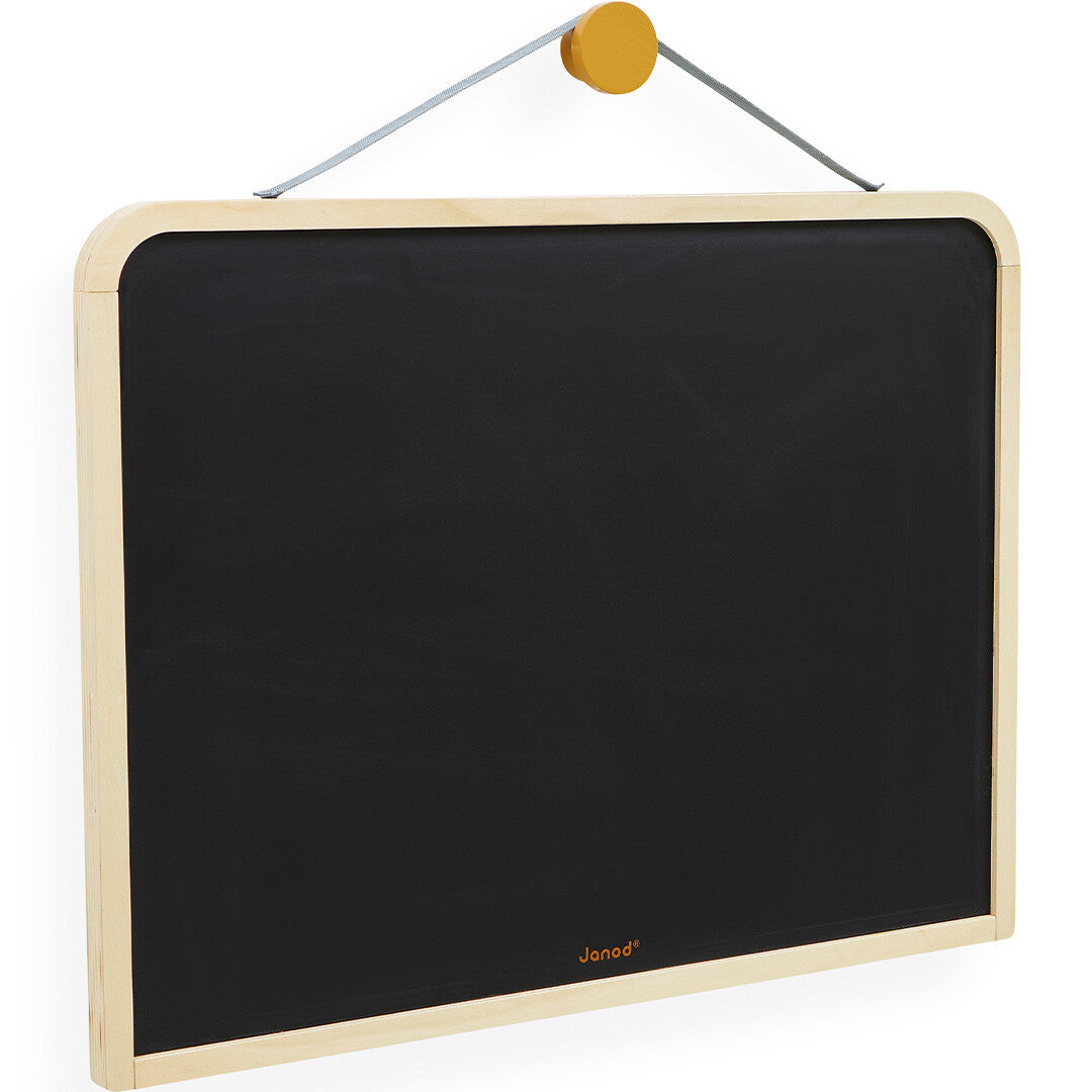 Janod hangend schoolbord met een licht houten frame en een effen zwart schrijfoppervlak, opgehangen aan een geel houten knopje.