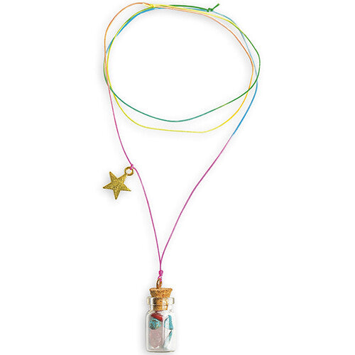Detail van een ketting met een glazen flesje gevuld met kleine steentjes en een gouden sterbedel aan een regenboogkleurig koord.