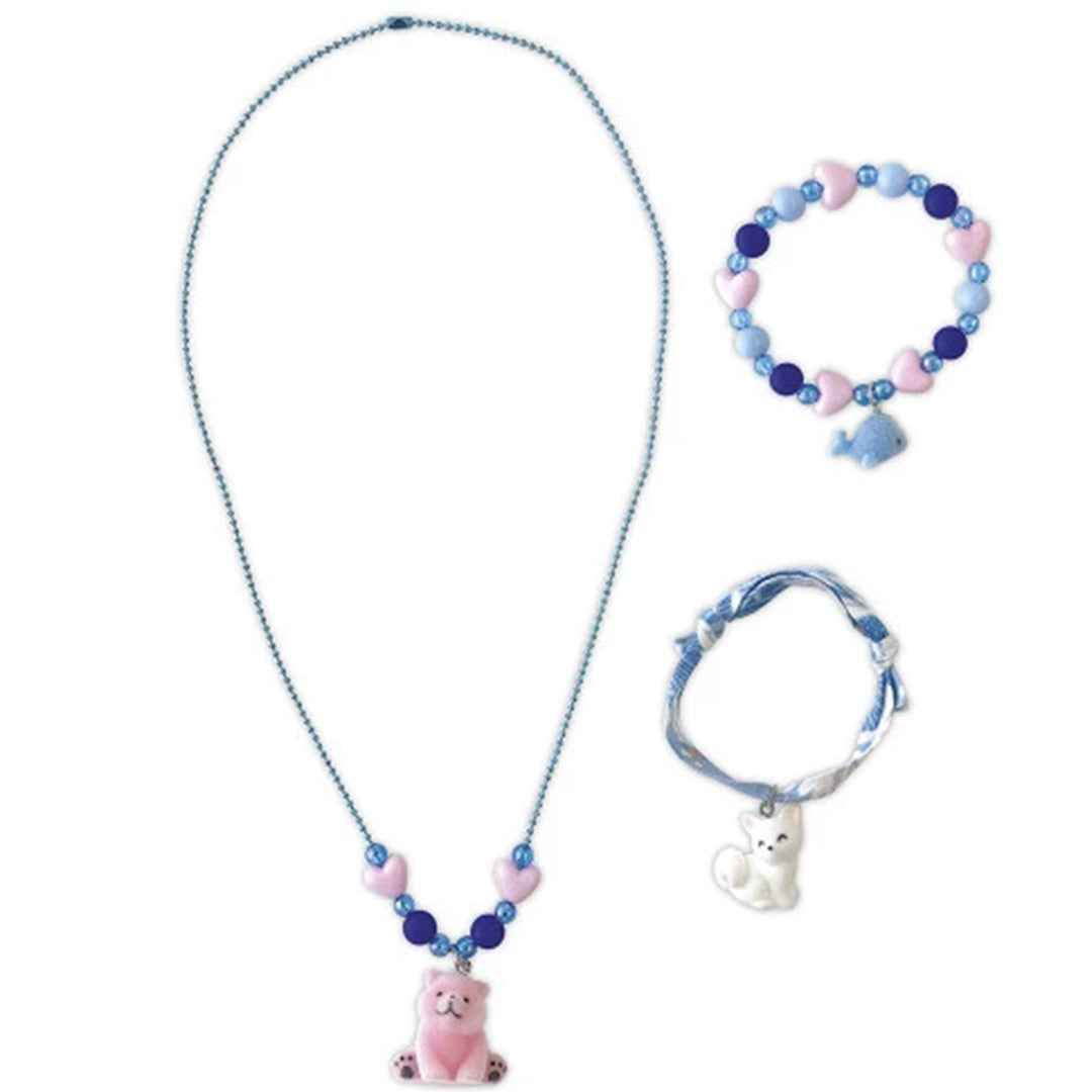 Drie gemaakte sieraden uit de set: een ketting met roze beer en twee armbanden met dierenhangers en hartjeskralen.
