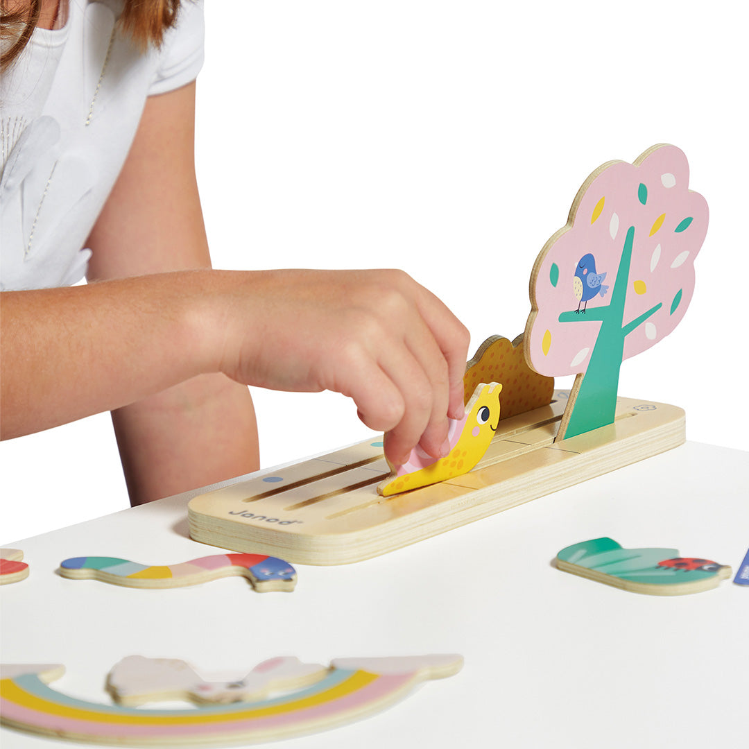 Een kinderhand demonstreert het Janod houten sorteerspel 'vind je plaats in de tuin' door een slakje te plaatsen.