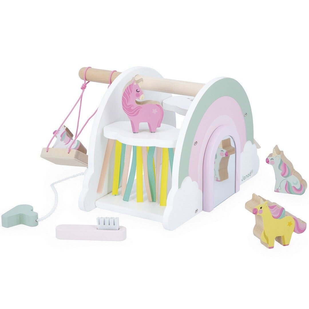 Janod houten eenhoorn speelset met regenbooghuis, spiegel, schommel, roze eenhoorn en verzorgingsaccessoires.