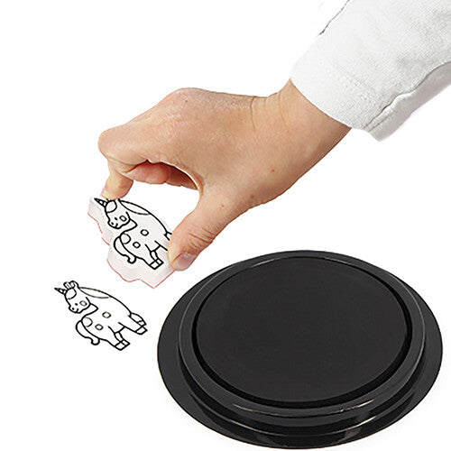 Een hand houdt twee Janod eenhoornstempels boven een zwarte stempelpad.