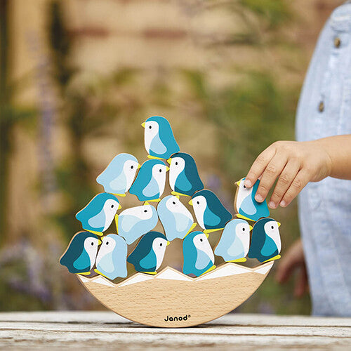 Een kinderhand plaatst een blauwe houten pinguïn op het Janod WWF evenwichtsspel.