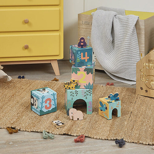 Janod WWF stapeltoren met dieren op een gevlochten mat in een kinderkamer, met een gele ladekast op de achtergrond.