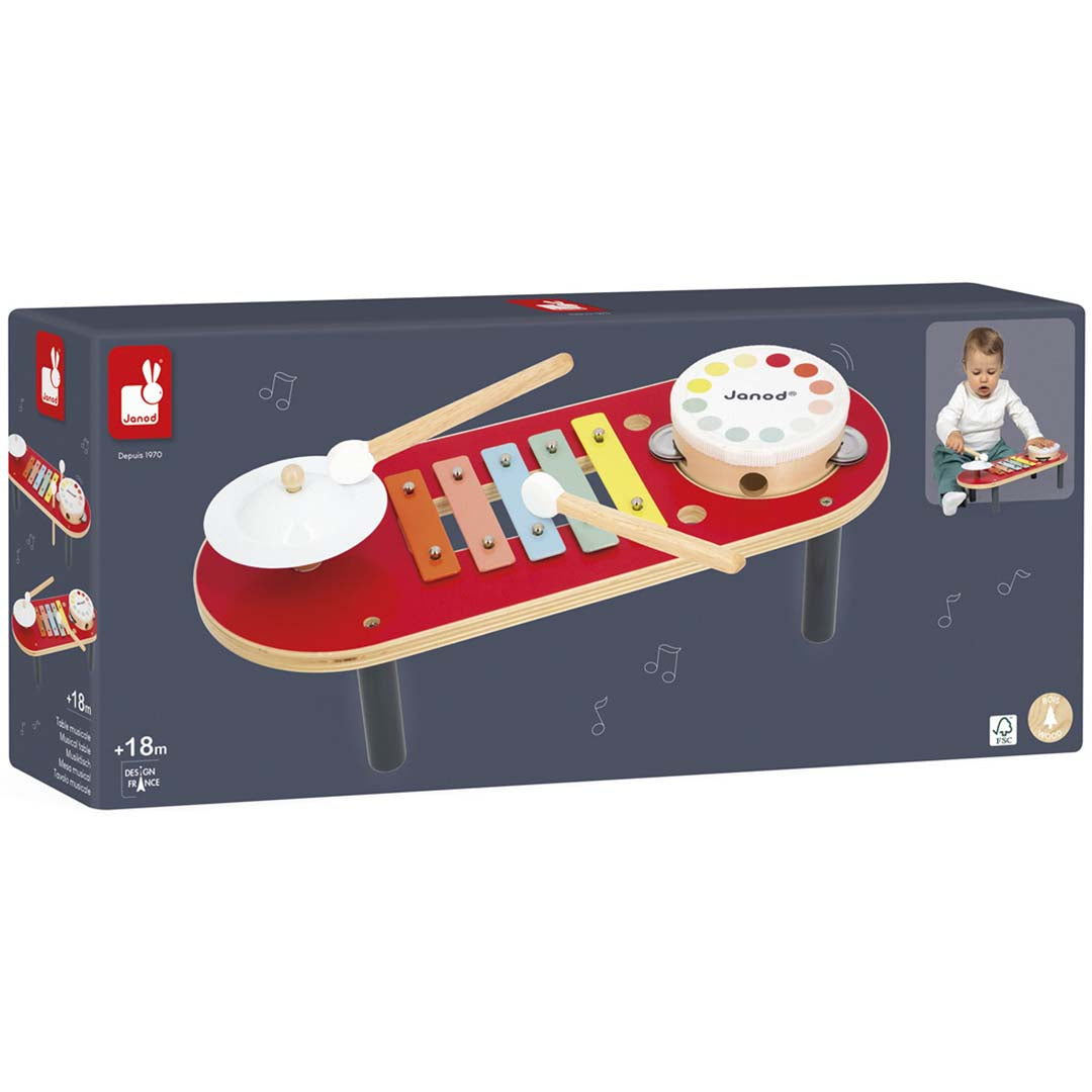 De verpakking van de Janod houten muziektafel met afbeeldingen van het speelgoed en een spelend kind.