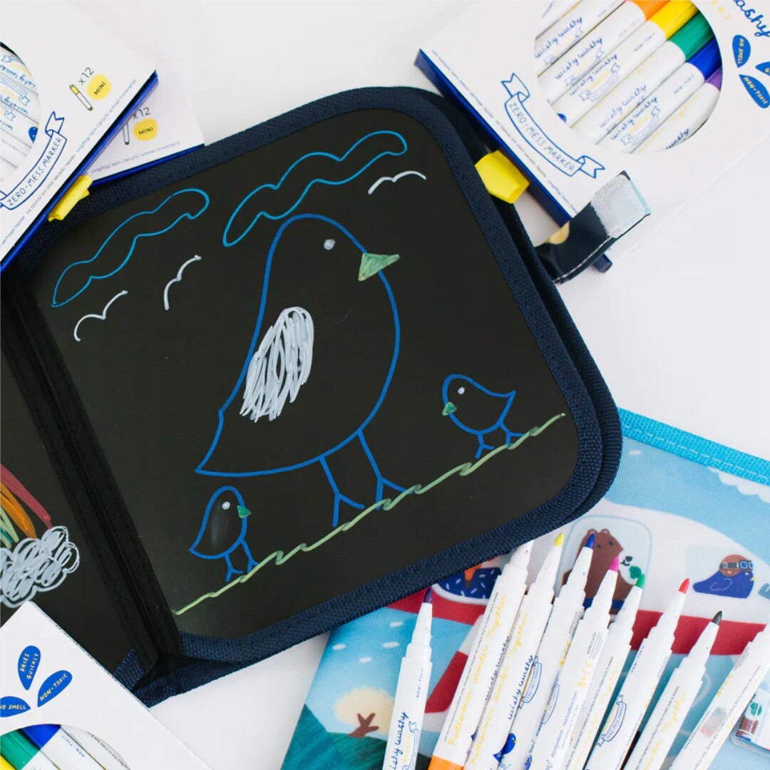 Een open Jaq Jaq Bird tekenboek met een tekening van vogels en diverse uitwisbare mini viltstiften ernaast.