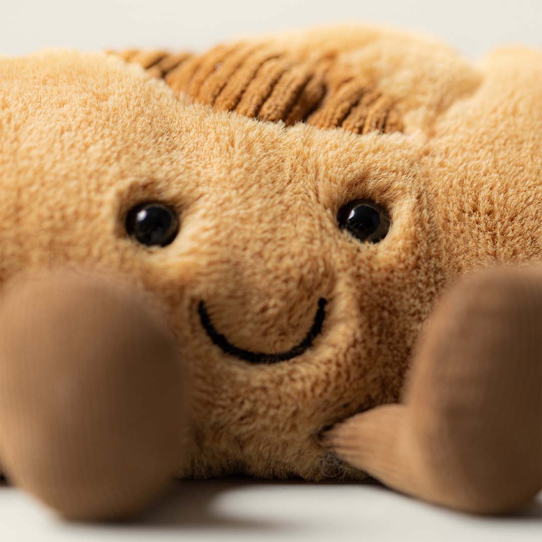 Close-up van het lachende gezicht van de Jellycat pluchen baguette knuffel.