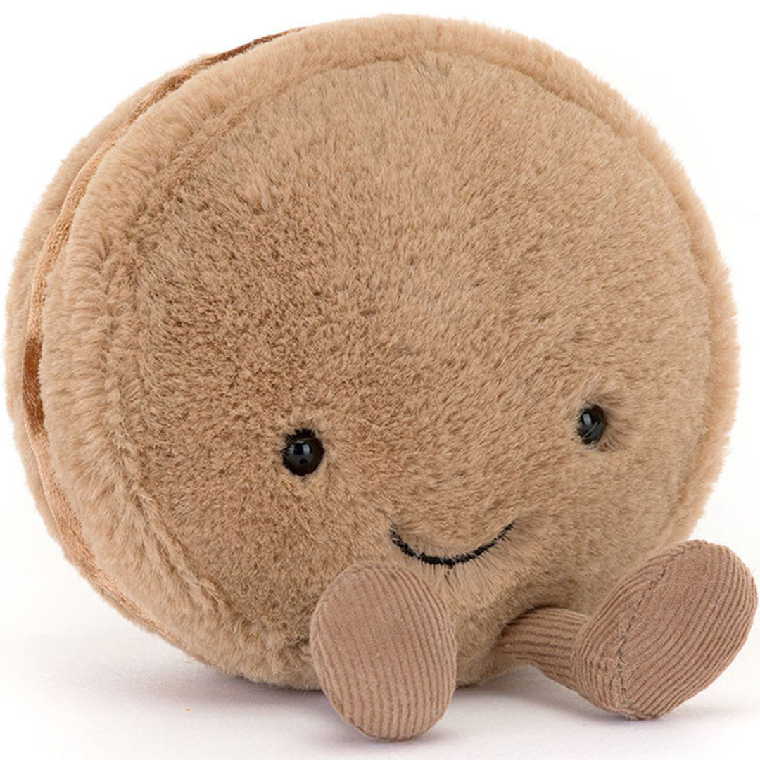 Jellycat amuseables knuffelmacaron chocola, liggend op zijn zij met een lachend gezichtje en kleine voetjes.