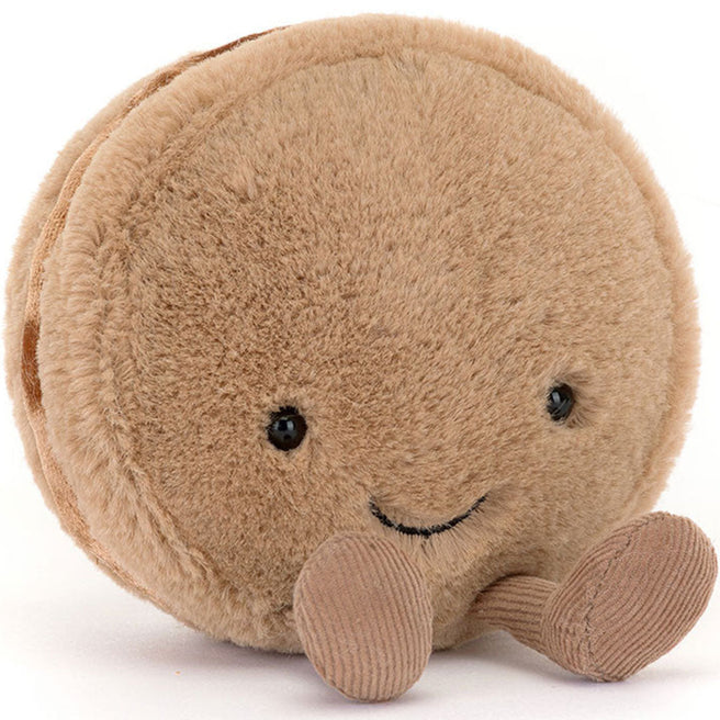 Jellycat amuseables knuffelmacaron chocola, liggend op zijn zij met een lachend gezichtje en kleine voetjes.
