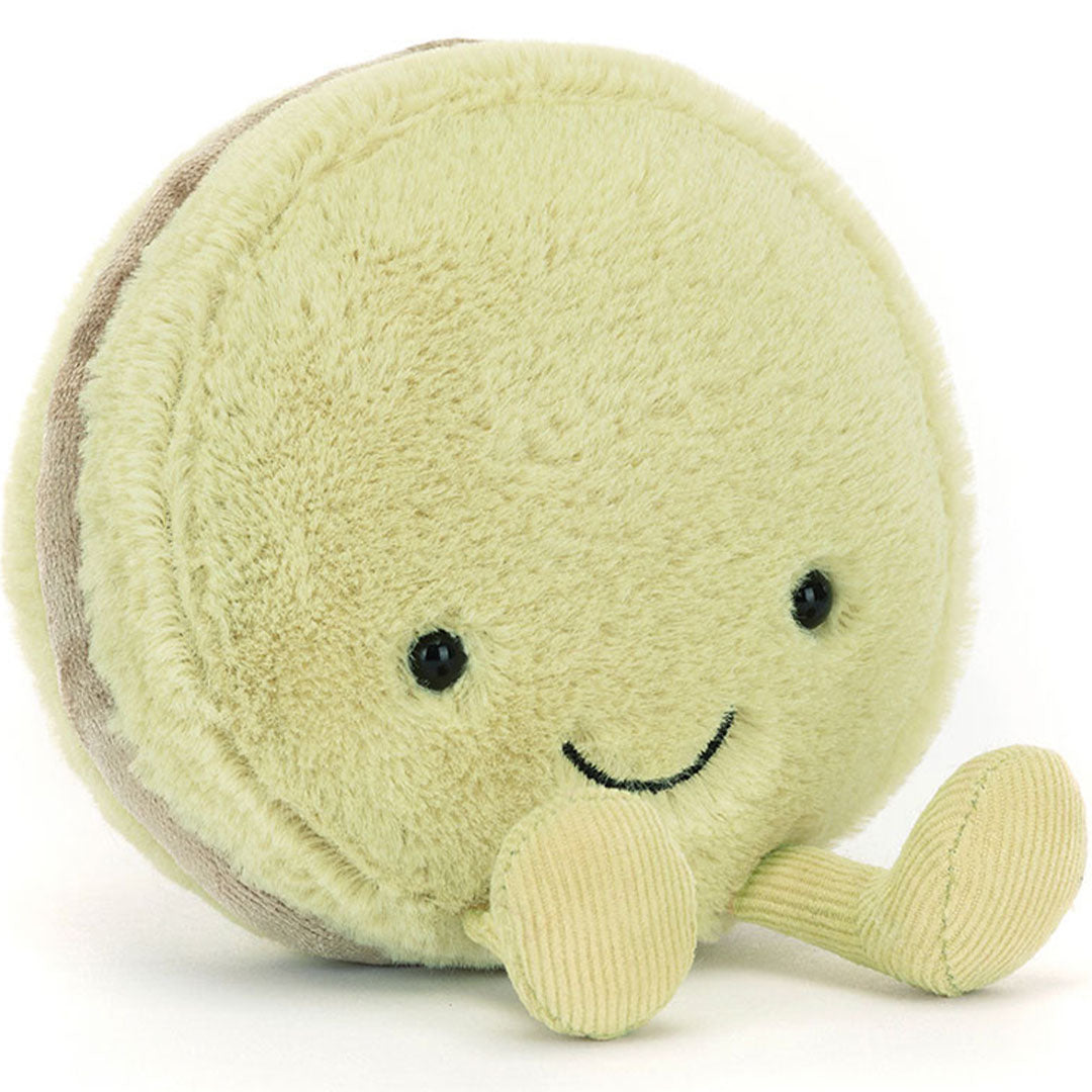 Jellycat pluchen pistache macaron knuffel met lachend gezicht en kleine voetjes, schuin gefotografeerd.