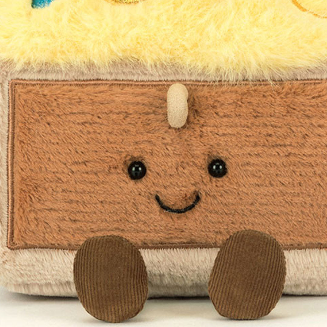 Detail van de Jellycat pluchen schatkist knuffel, met een vrolijk gezichtje en kleine bruine voetjes.