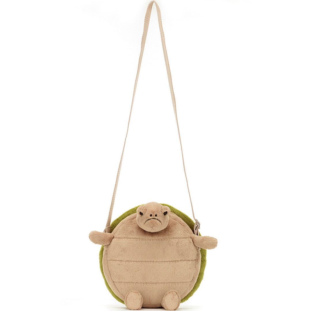 De Jellycat schildpad kindertas hangend aan de schouderband, recht van voren gezien.