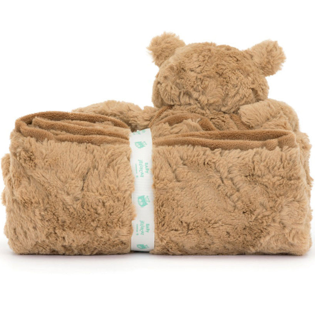Vooraanzicht van het Jellycat knuffeldekentje, opgerold met de bruine pluchen beer erachter en een wit lint in het midden.