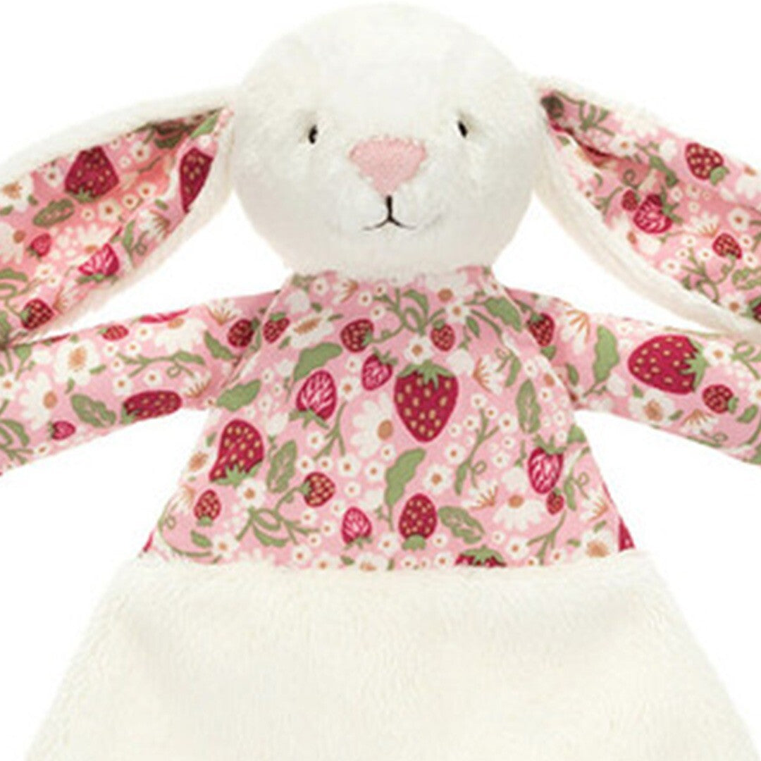 Detailopname van de kop en het roze lijfje met aardbeienpatroon van de Jellycat konijnen knuffeldoek.