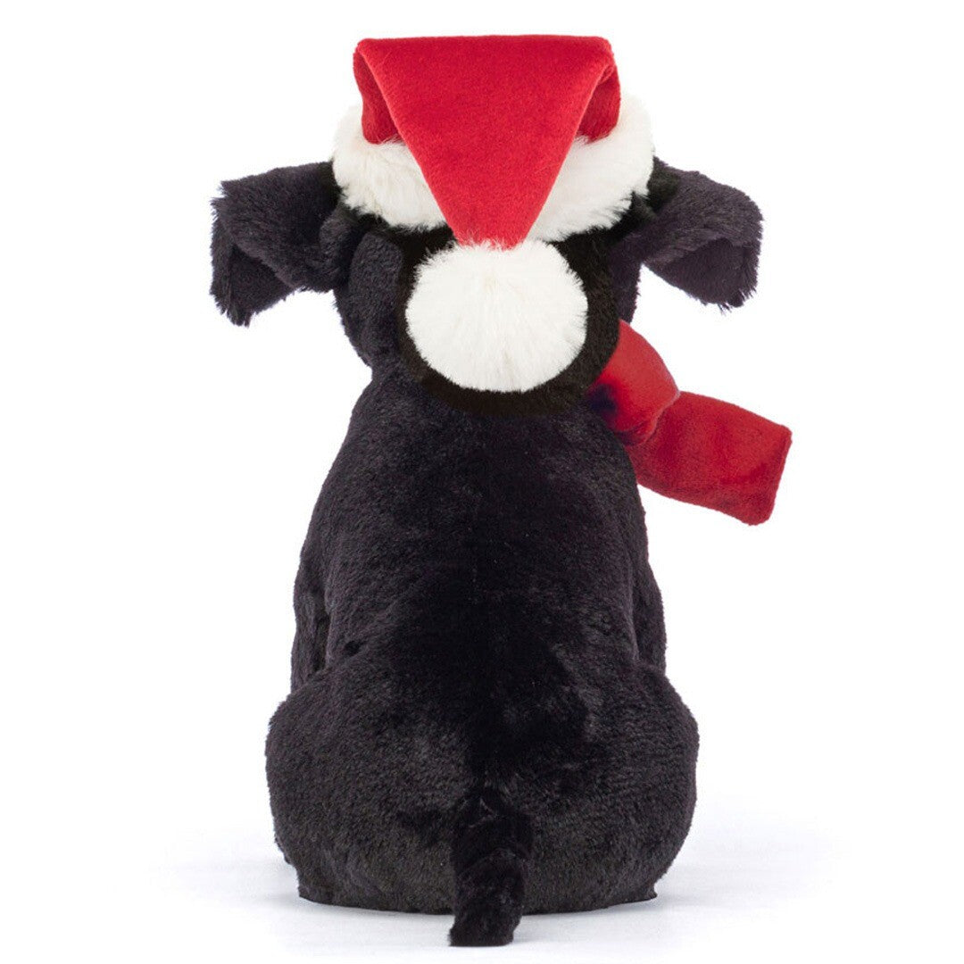 Jellycat knuffelhond Pippa, een zwarte pluchen hond met rode kerstmuts en rode strik, zit van achteren.