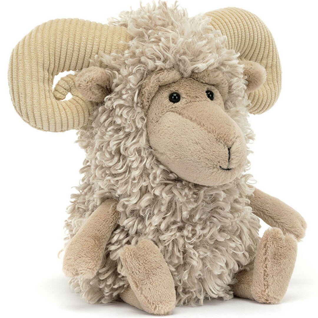 Jellycat pluchen ram met beige krullende vacht en corduroy hoorns, zittend en schuin gefotografeerd.