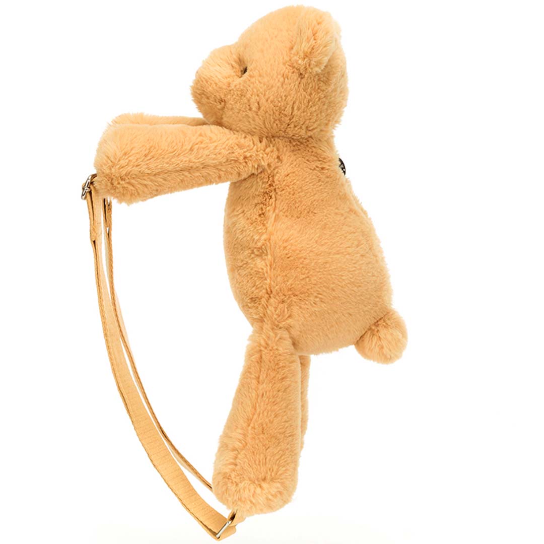 Jellycat peuterrugzak in de vorm van een lichtbruine knuffelbeer, van de zijkant gezien met de schouderbanden.