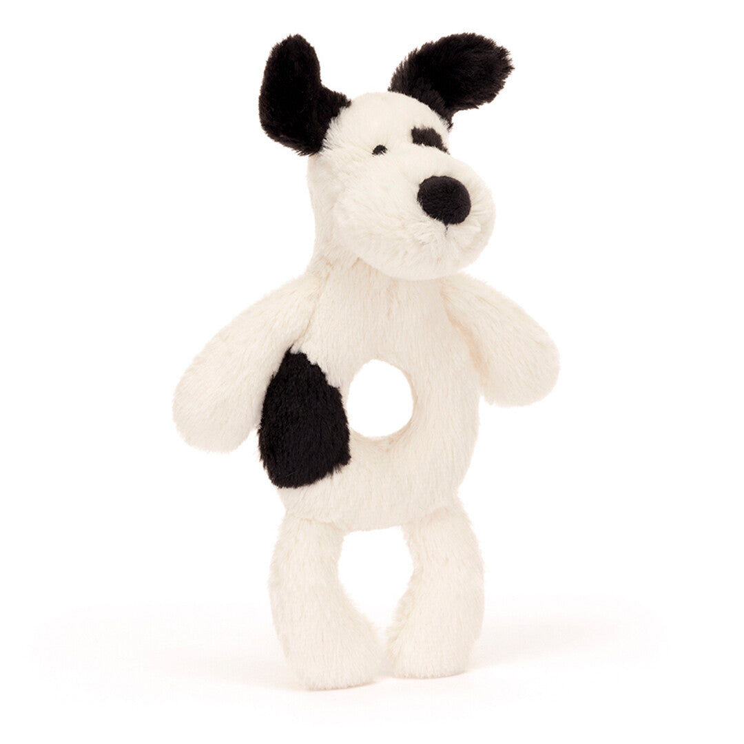 Jellycat rammelaar in de vorm van een wit met zwart gevlekte puppy, schuin van voren.
