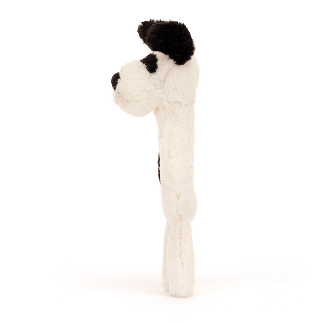 Jellycat rammelaar in de vorm van een wit met zwart gevlekte puppy, van de zijkant.