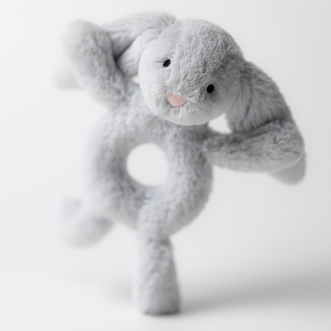 Jellycat grijze pluche konijn rammelaar, schuin van voren gefotografeerd.